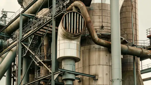 Instalação industrial com tubulações, vasos e estruturas metálicas de uma planta de processo.