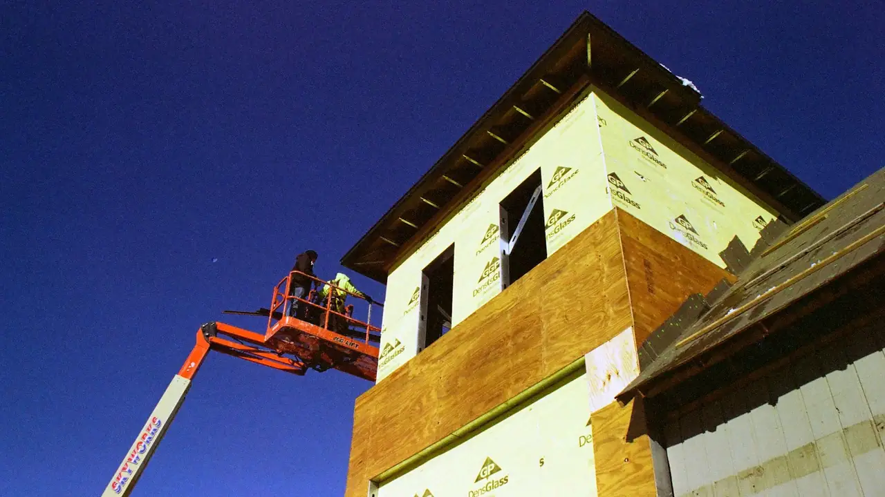 Plataforma elevatória articulada com operador no cesto, em obra ao entardecer.